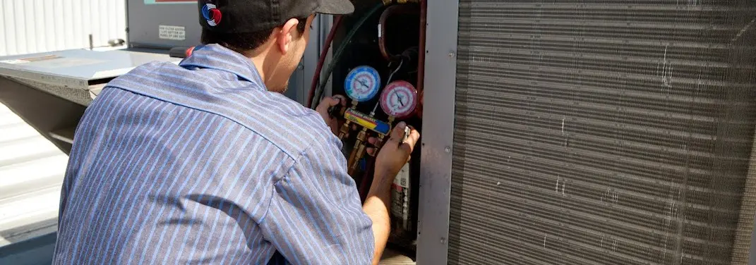 HVAC technician servicing a condenser unit in Midland