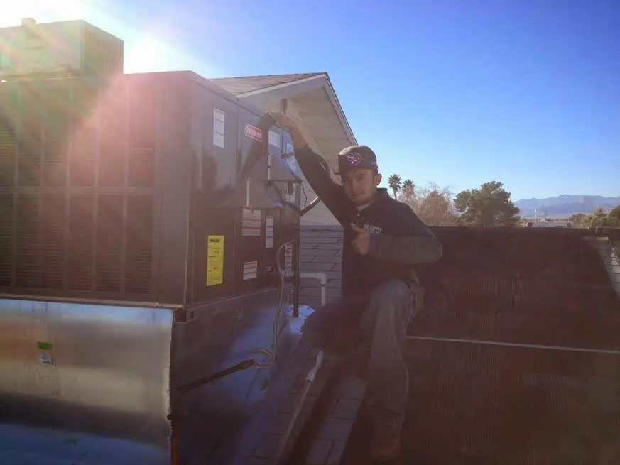 HVAC technician performing Air Duct Cleaning on a rooftop unit in Midland